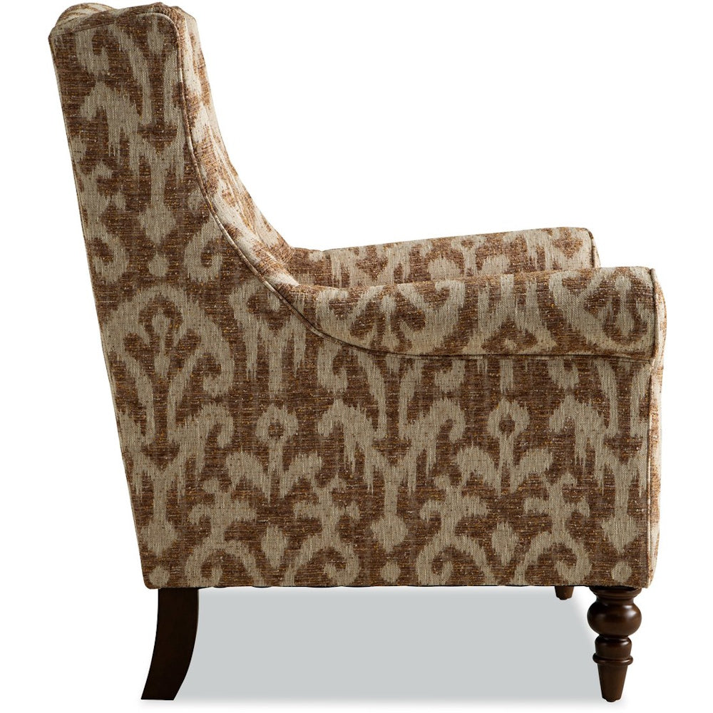 Side view of an upholstered armchair with a brown ikat pattern and dark turned wood legs.