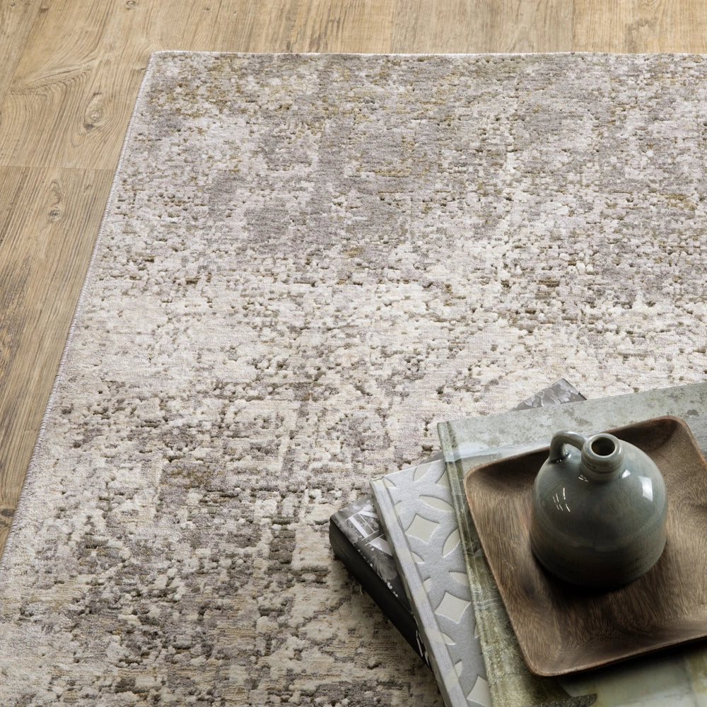 Top-down view of the gray, taupe, and cream area rug styled with stacked books and a ceramic jug on a wooden tray.