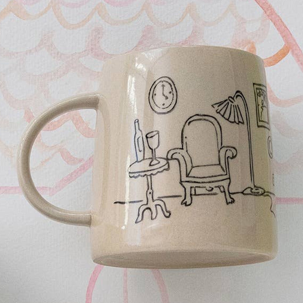 Cream ceramic mug featuring a black hand-drawn cozy living room scene with an armchair and lamp.