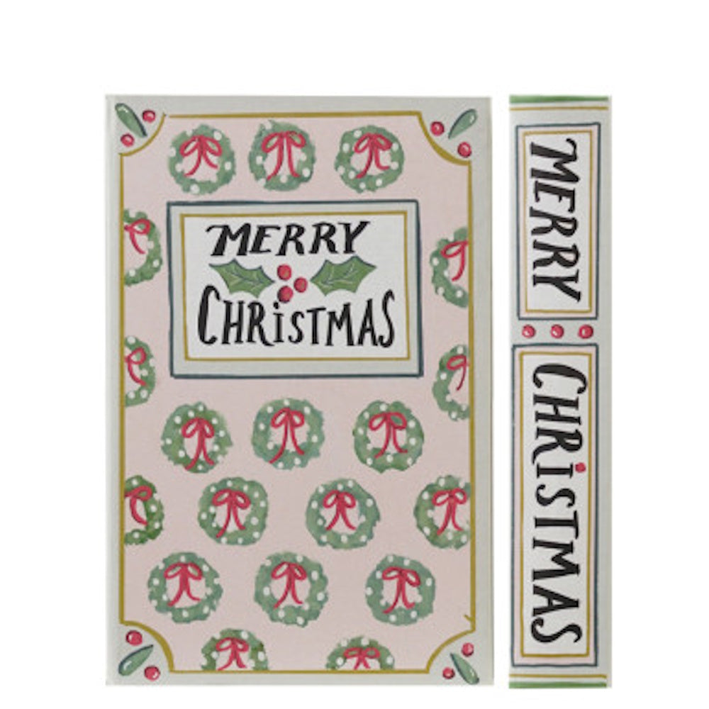 Decorative book storage box reading "MERRY CHRISTMAS" with a pink, wreath-patterned cover.