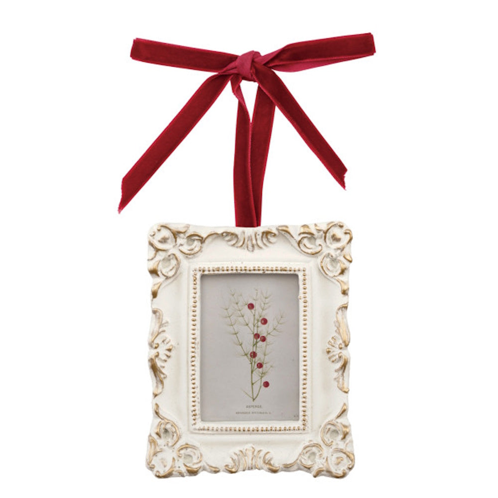 Ornate white and gold picture frame ornament tied with a red velvet ribbon bow.