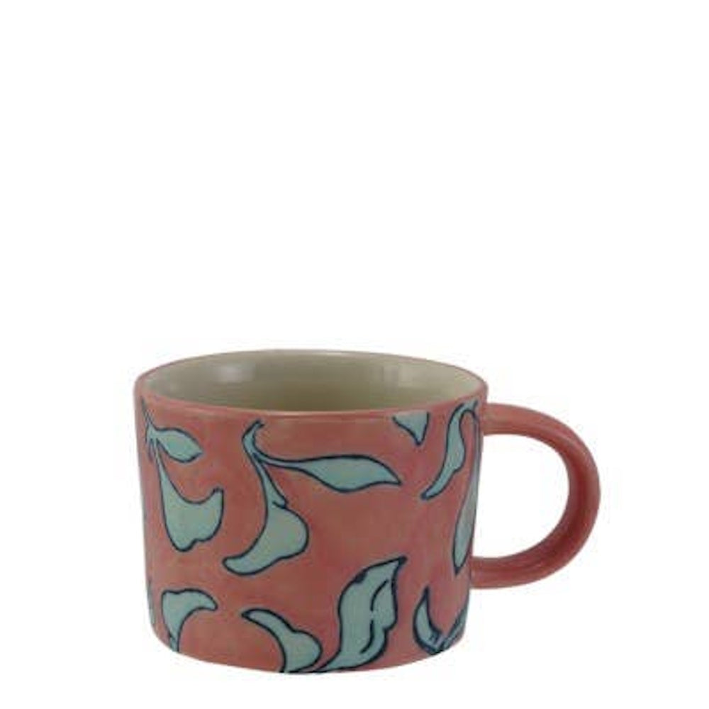 Pink ceramic mug decorated with a blue leaf botanical pattern and a matching pink handle.