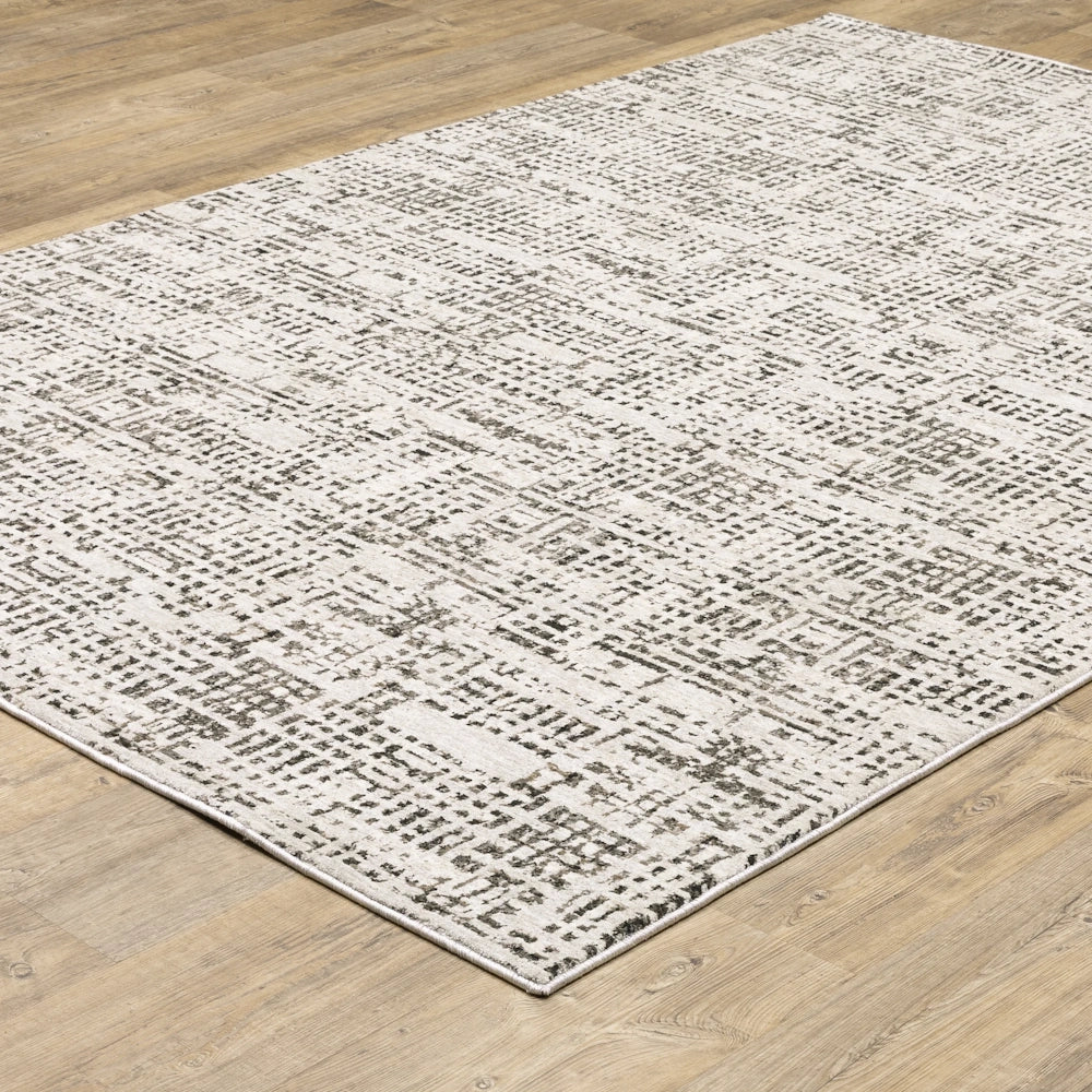 Angle view of the gray and cream area rug laid out on a light wood floor.