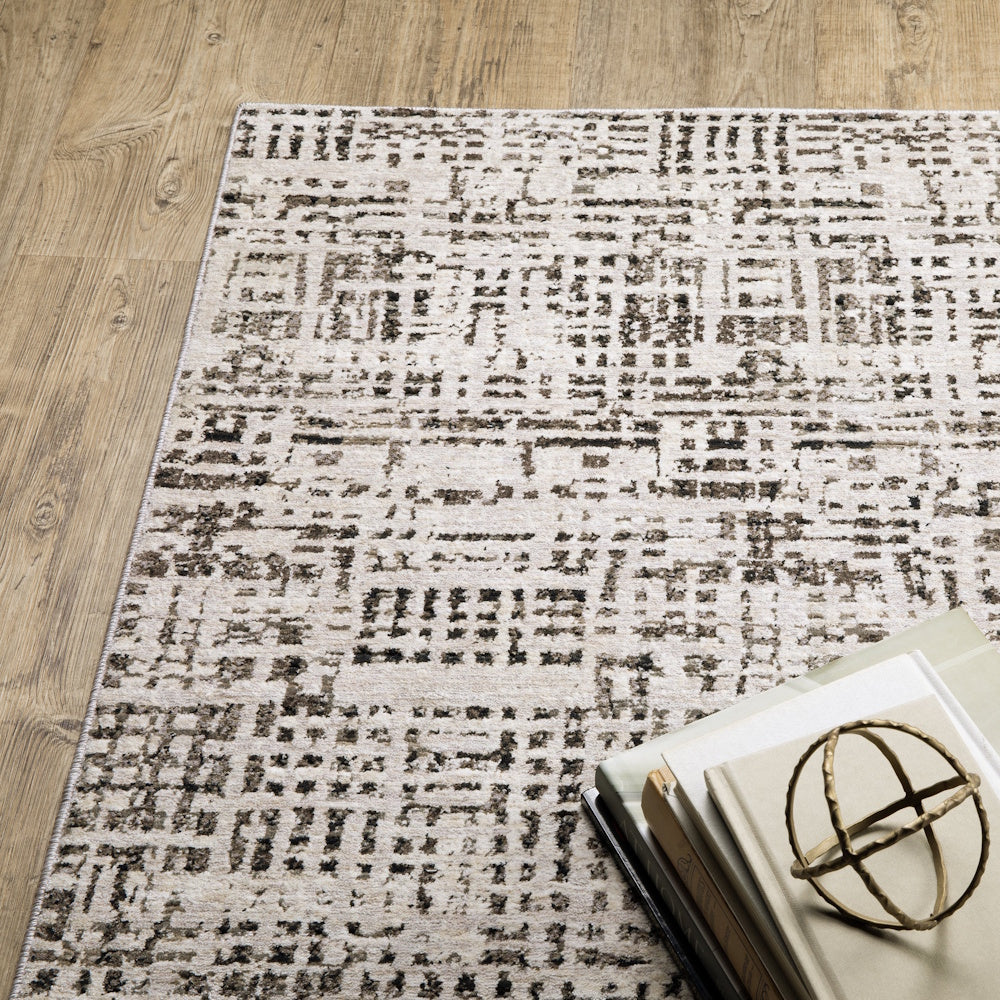 Top-down view of the gray and cream area rug styled with a stack of books and a gold decorative sphere on a wooden floor.