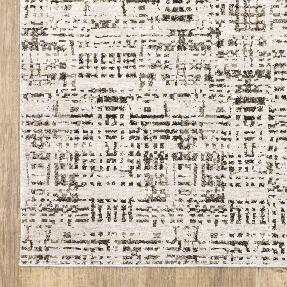 Close-up view of the gray and cream area rug showing the edge pattern on a wooden floor.