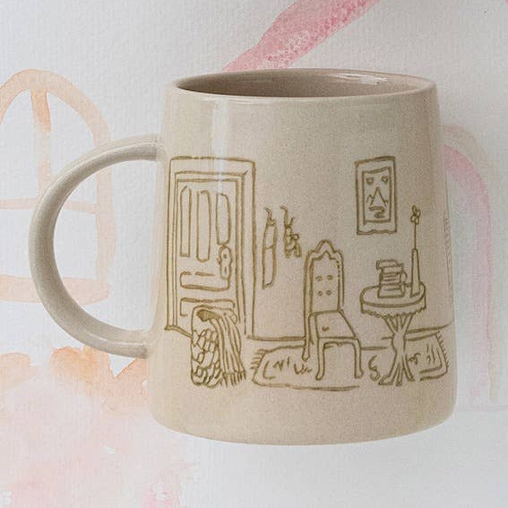 Cream stoneware mug featuring a line-drawn, hand-stamped illustration of a cozy home interior.
