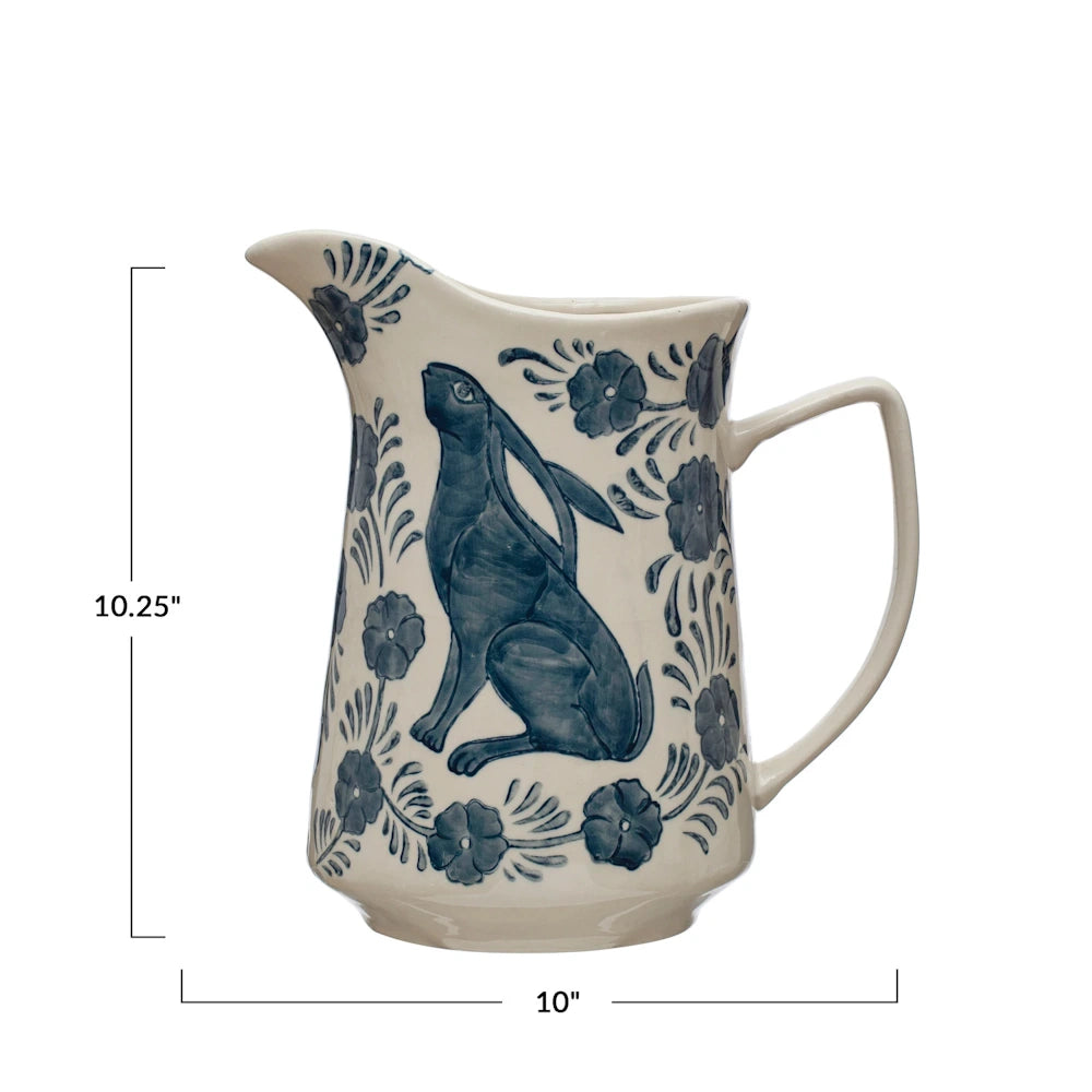 Hand-painted blue stoneware pitcher with rabbit and floral design, 10.25 inches tall by 10 inches wide.