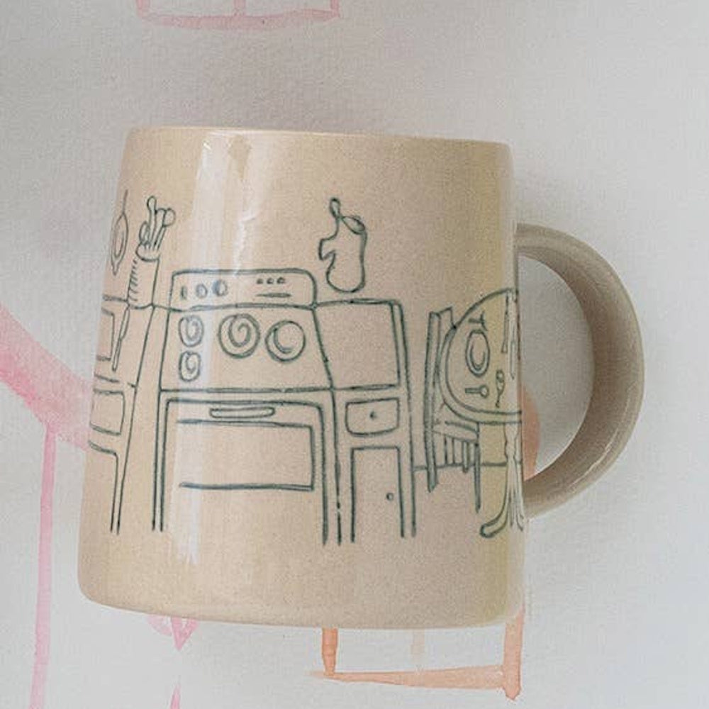 Beige ceramic mug with black line art illustration of a kitchen scene including a stove and table.