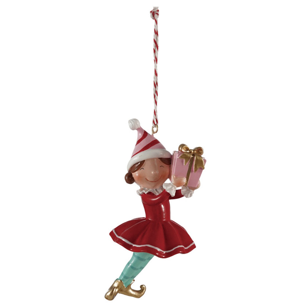 Whimsical elf Christmas ornament wearing a red dress and striped hat, holding a pink gift box.