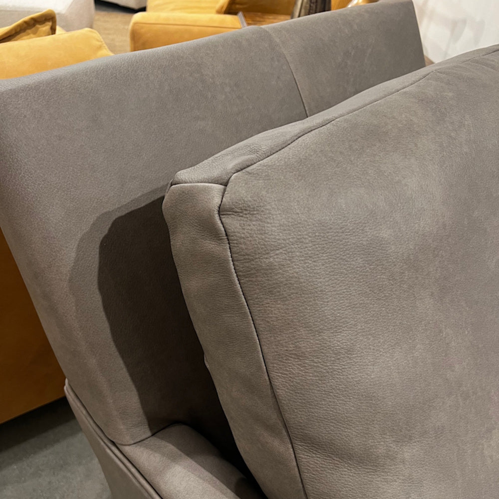 Close-up view of a grey leather armchair's backrest and padded cushion texture.