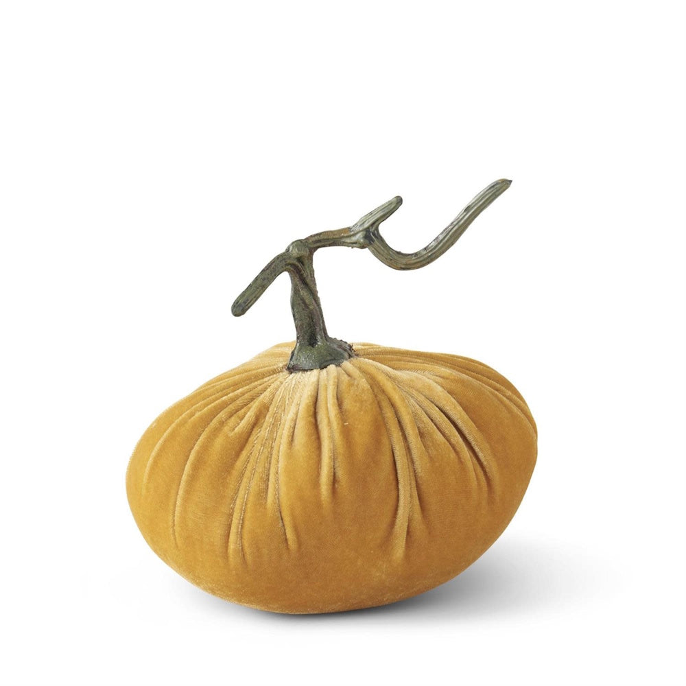 Plush golden-yellow velvet pumpkin decoration with a long, twisting green stem on a white background.