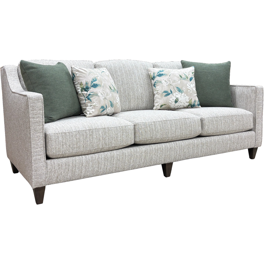 White textured fabric sofa with three cushions, green and floral pillows and dark tapered legs.
