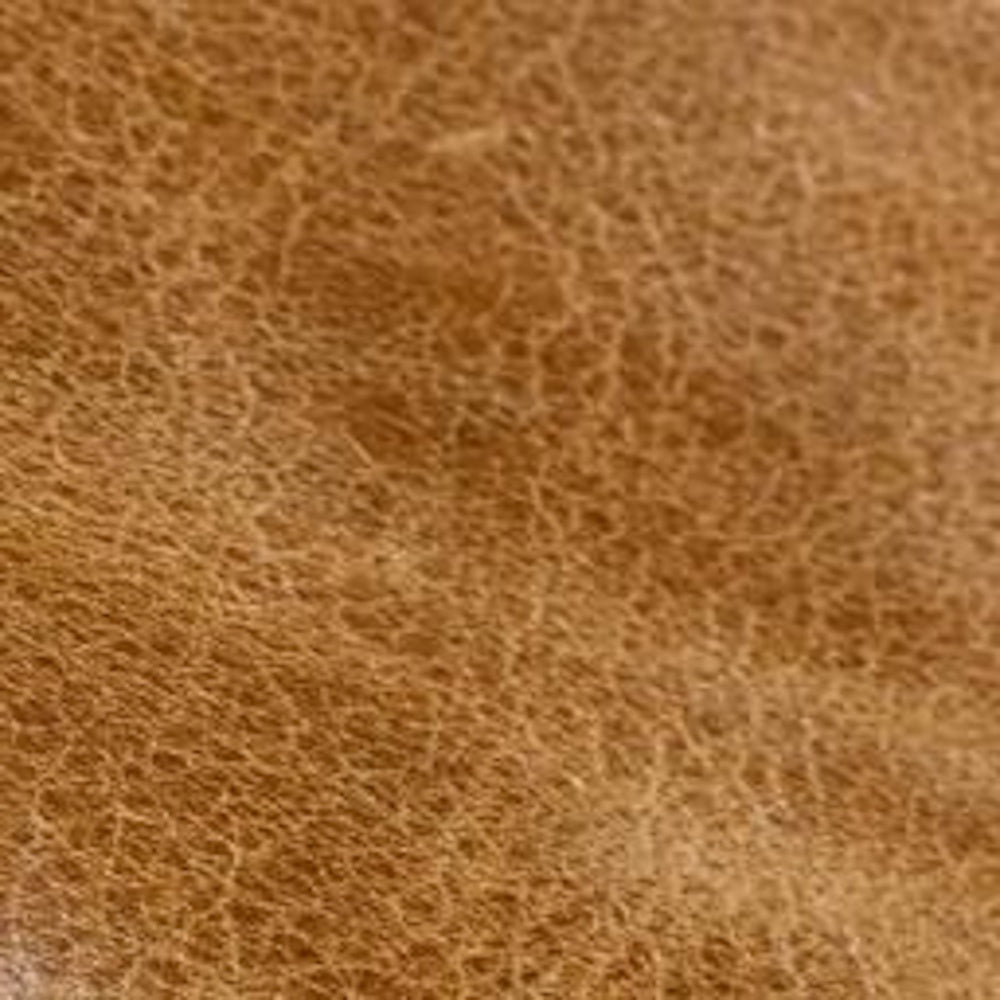 Close-up macro texture of distressed camel tan leather upholstery.