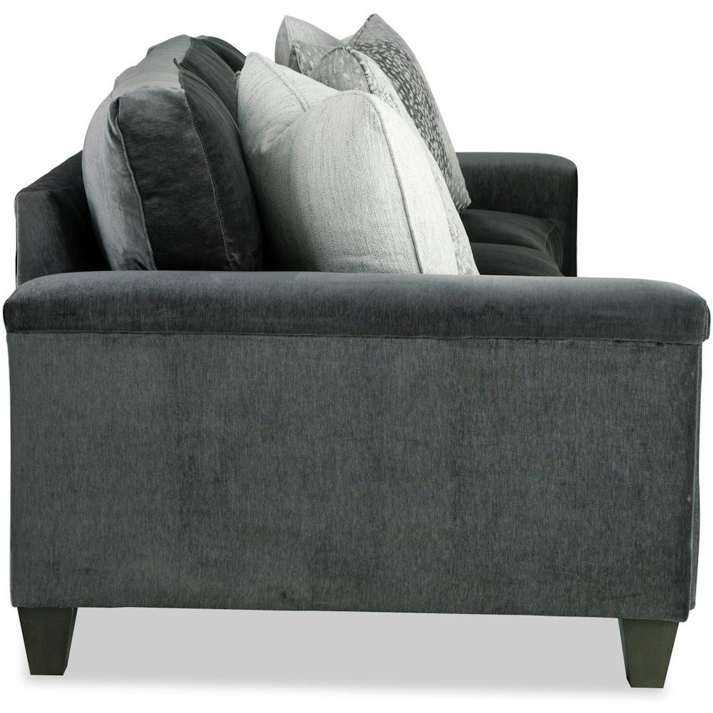 Side view of a dark charcoal gray velvet sofa featuring plush back cushions and light throw pillows.