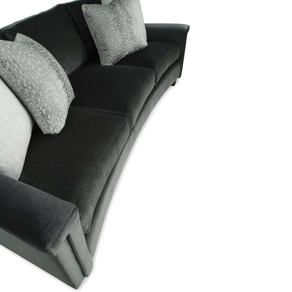 High-angle view of a dark charcoal velvet three-cushion sofa styled with patterned throw pillows.