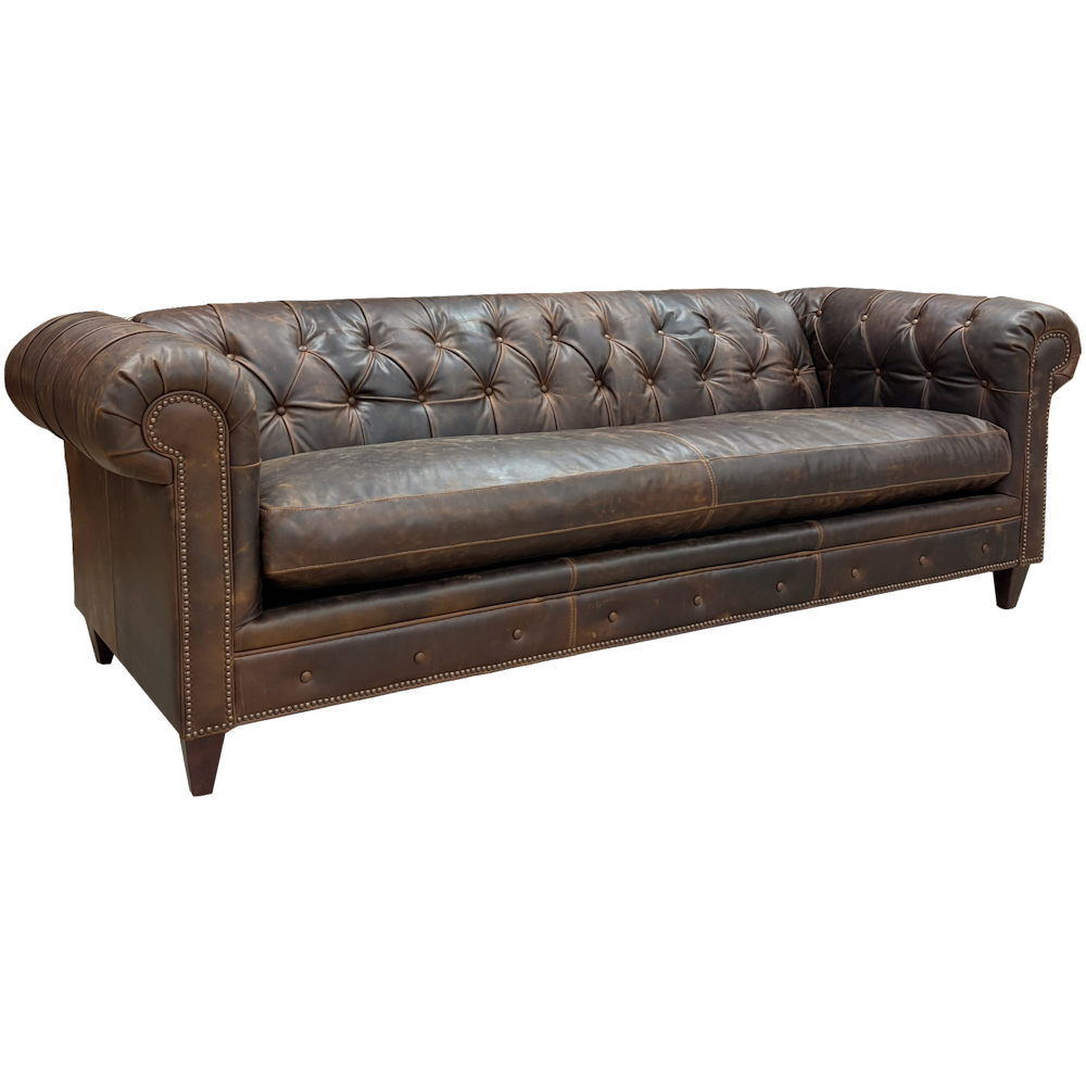 Brown leather Chesterfield sofa with tufted back, rolled arms, and nailhead trim on a black background.