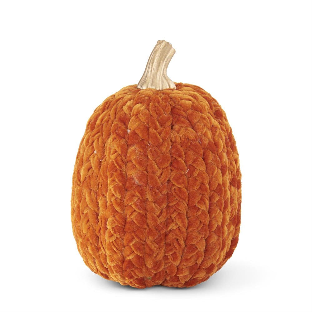 A textured, rust-orange braided knit pumpkin with a gold stem on a solid white background.