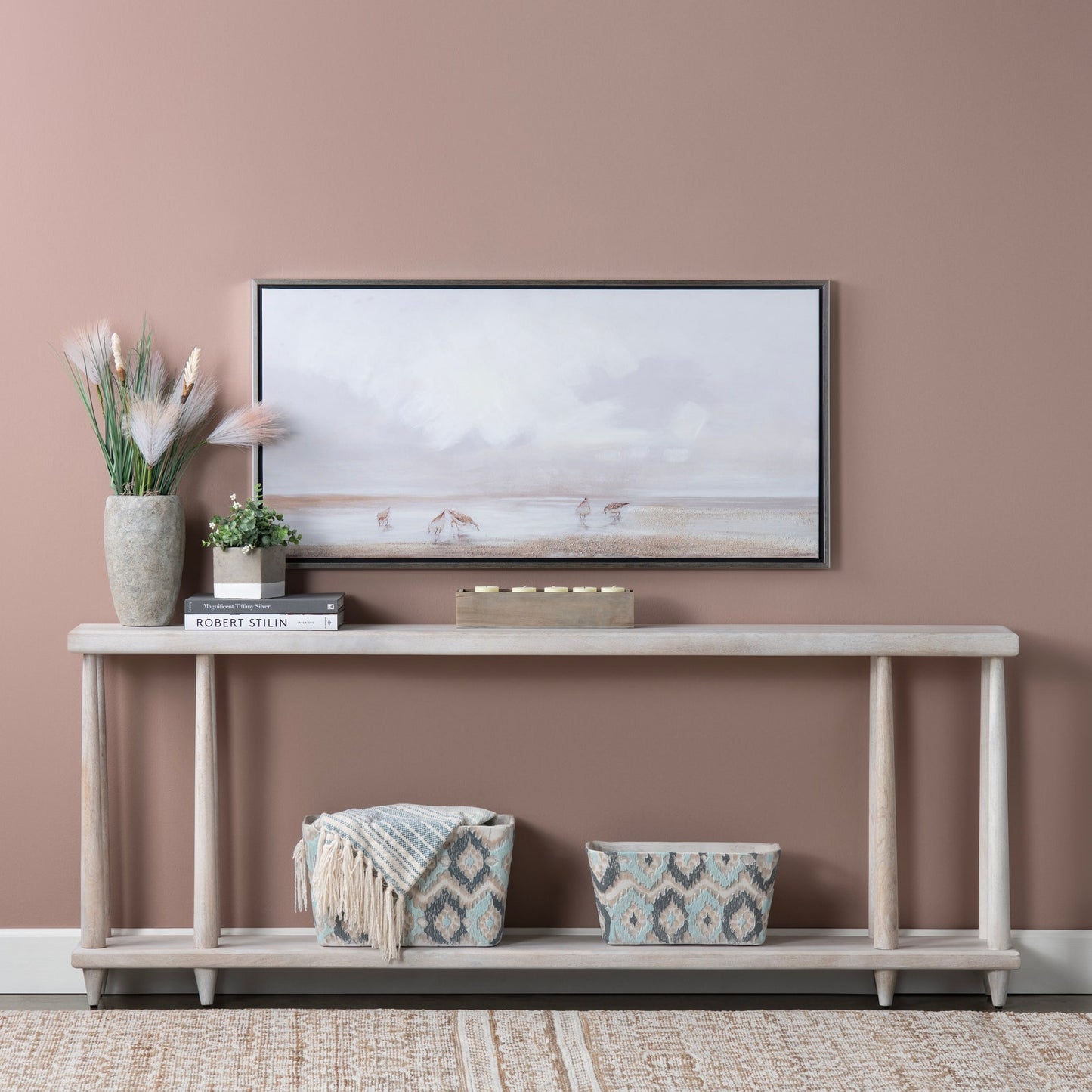 Console table with decorative items against a pink wall