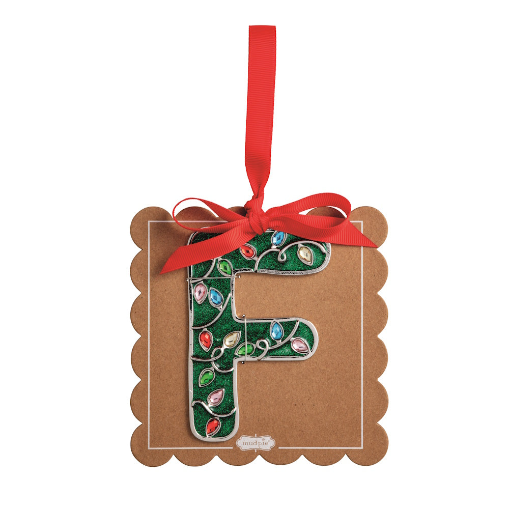 Sparkly green Christmas initial ornament letter F on a scalloped brown card with a red hanging ribbon.