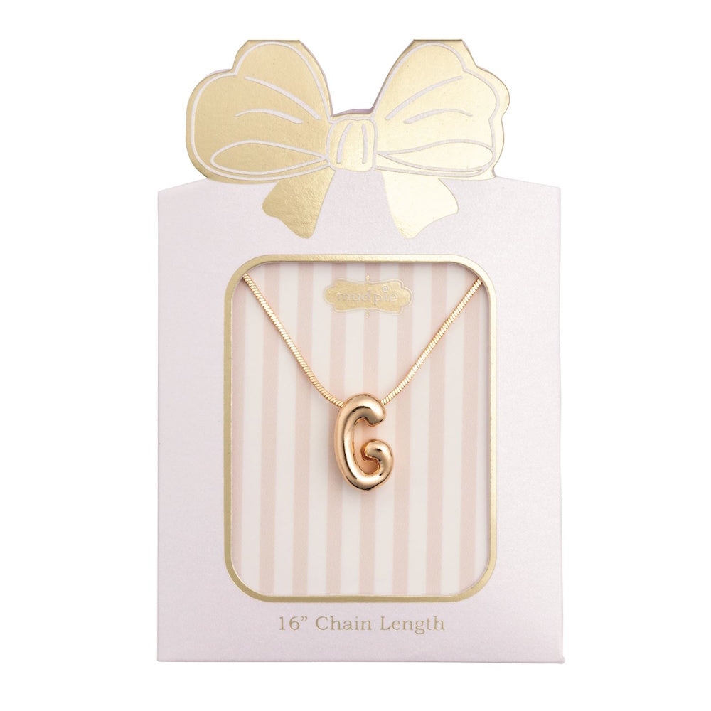 Gold initial "G" pendant necklace packaged in a pink box with a gold bow design.