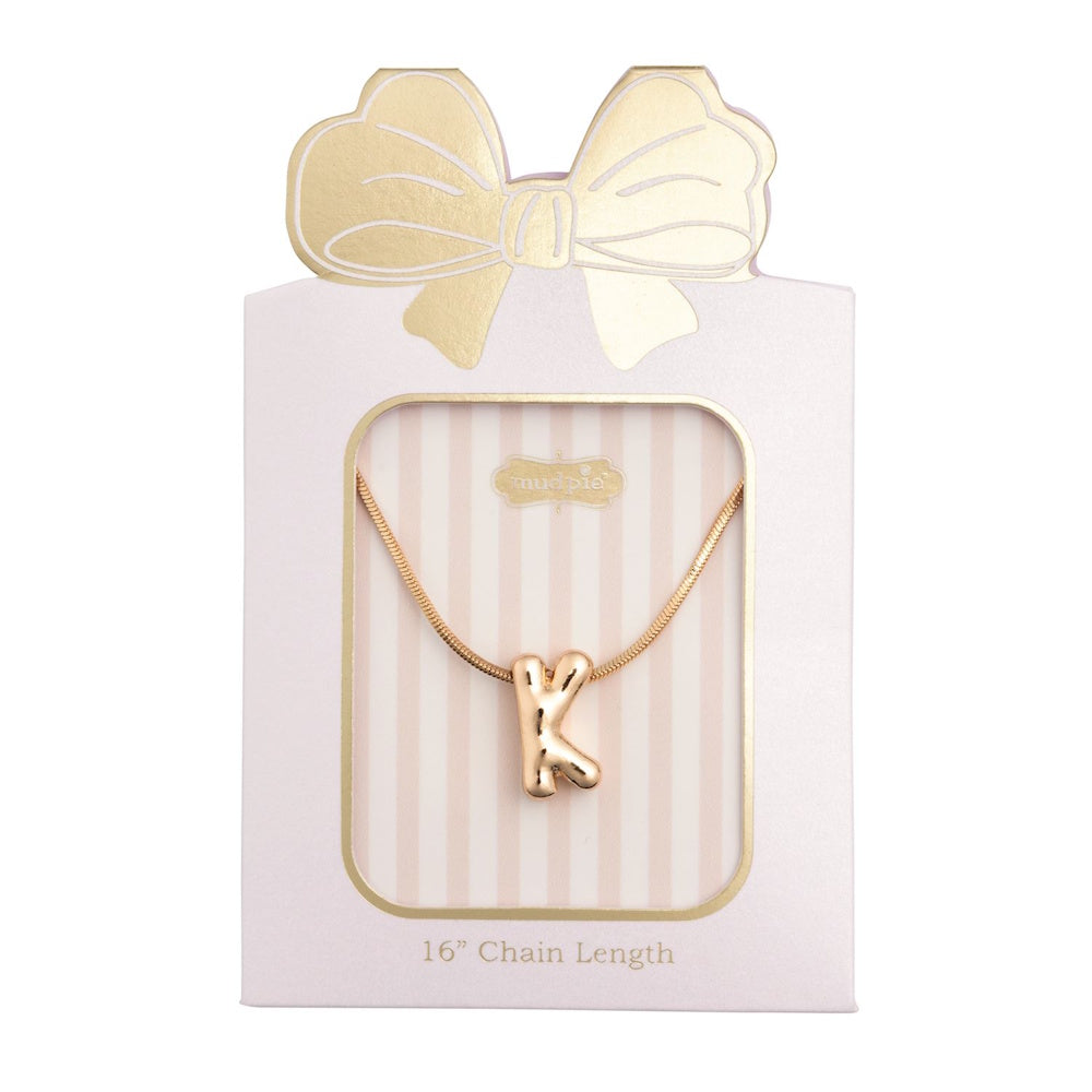Gold initial "K" pendant necklace packaged in a pink box with a gold bow design.