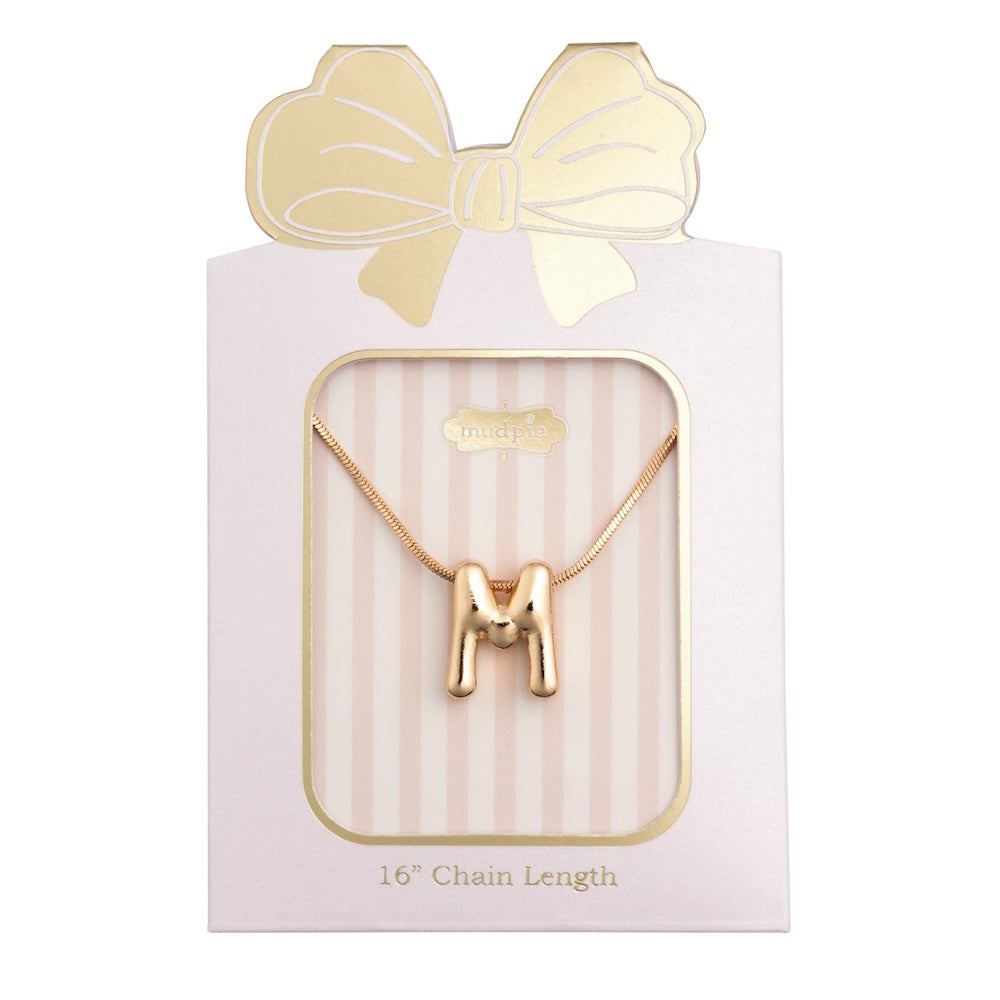 Gold initial "M" pendant necklace packaged in a pink box with a gold bow design.