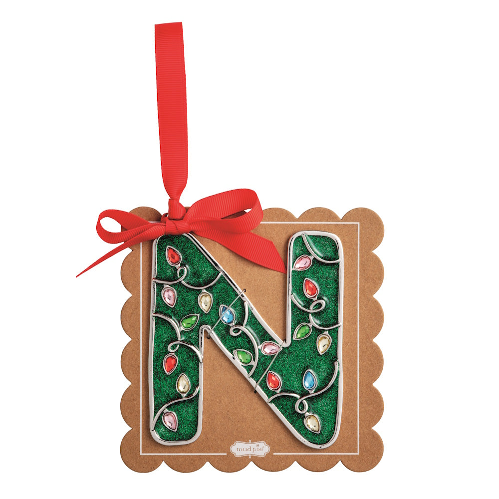 Sparkly green Christmas initial ornament letter N on a scalloped brown card with a red hanging ribbon.