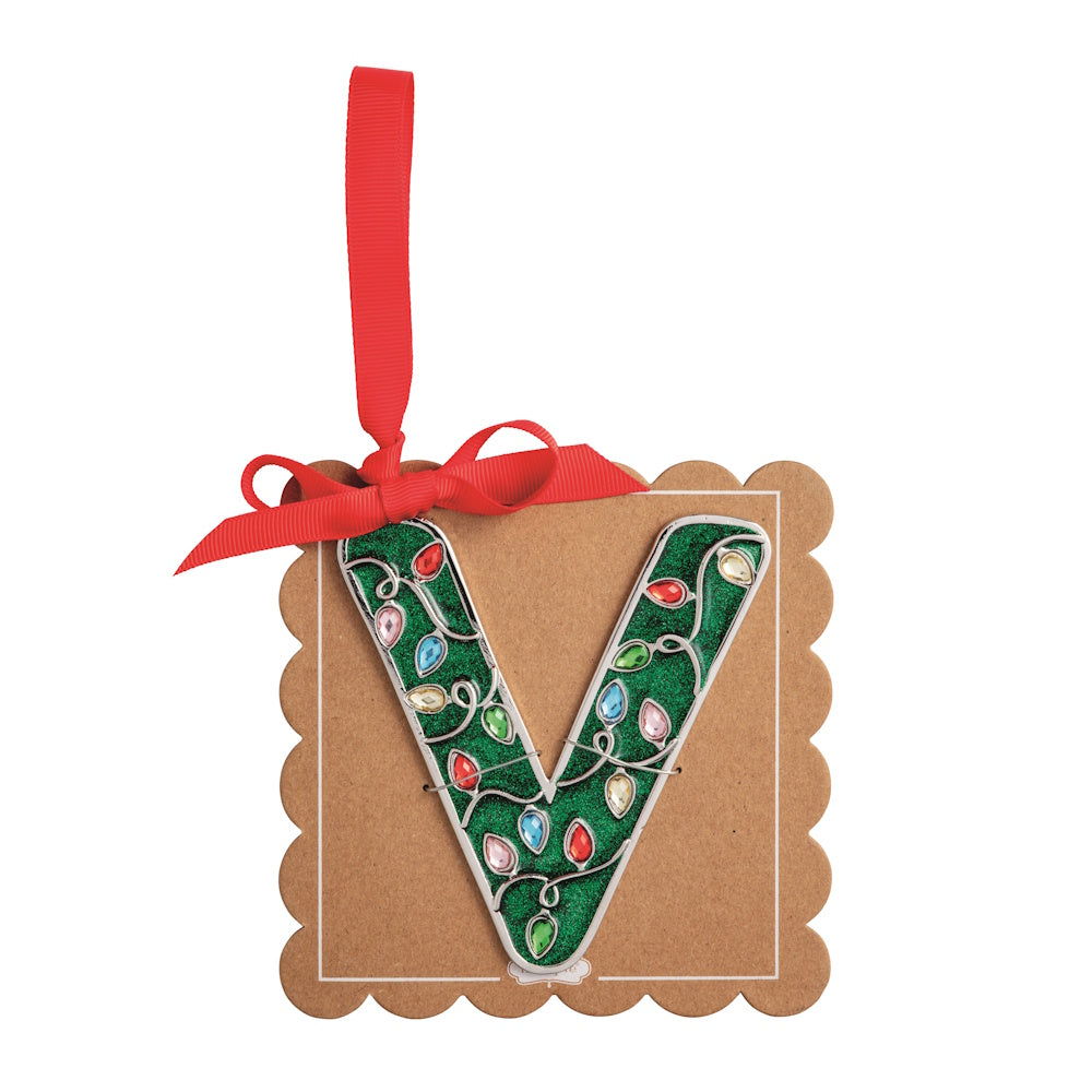 Sparkly green Christmas initial ornament letter V on a scalloped brown card with a red hanging ribbon.