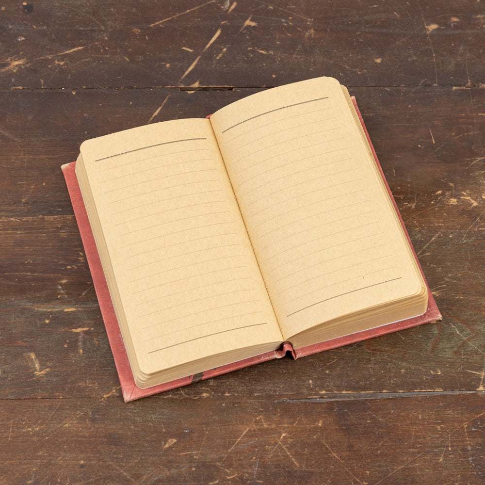 An open lined journal with vintage-style kraft paper pages resting on a rustic wooden surface.