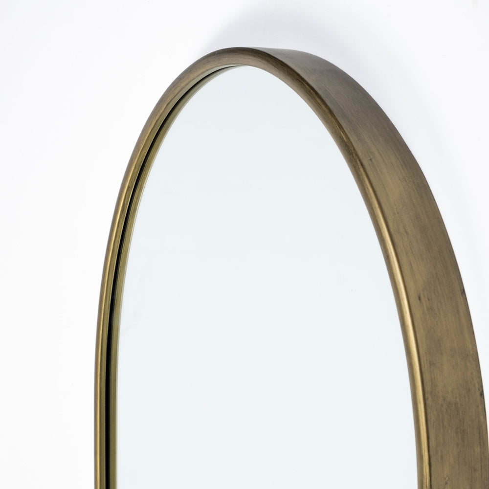 Close-up detail of the rounded top arch of a mirror with a brushed antique gold metal frame.