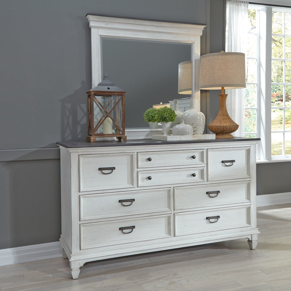 Off-white mirror mounted above a matching two-tone dresser in a styled bedroom setting.
