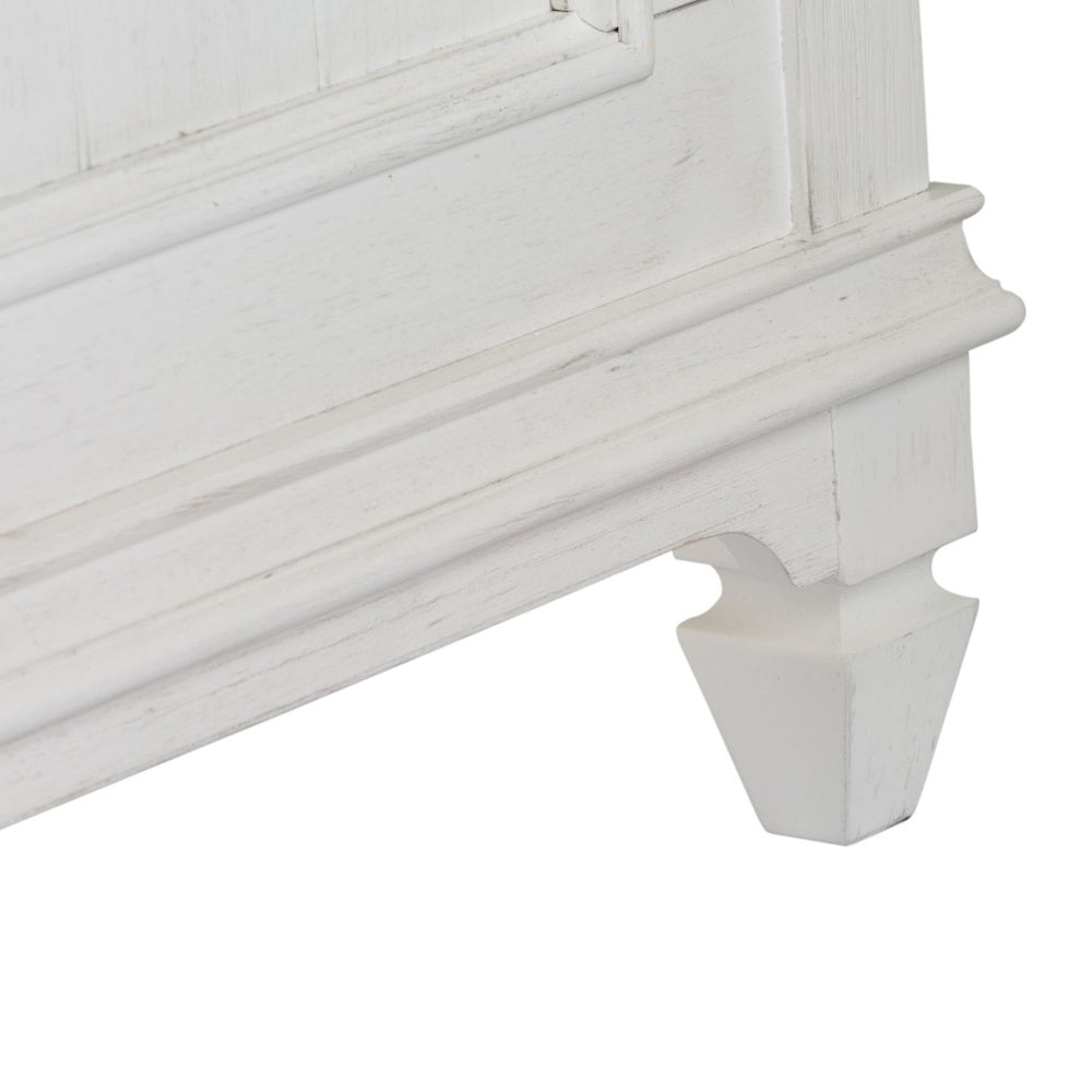 Close-up of the carved white wooden foot and molding detail on the panel bed base.