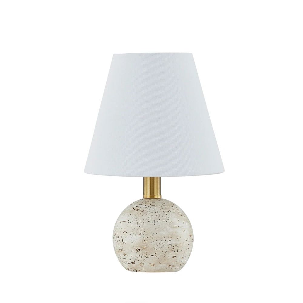Small table lamp with a white tapered shade, gold neck, and a round, textured cream-colored stone base.