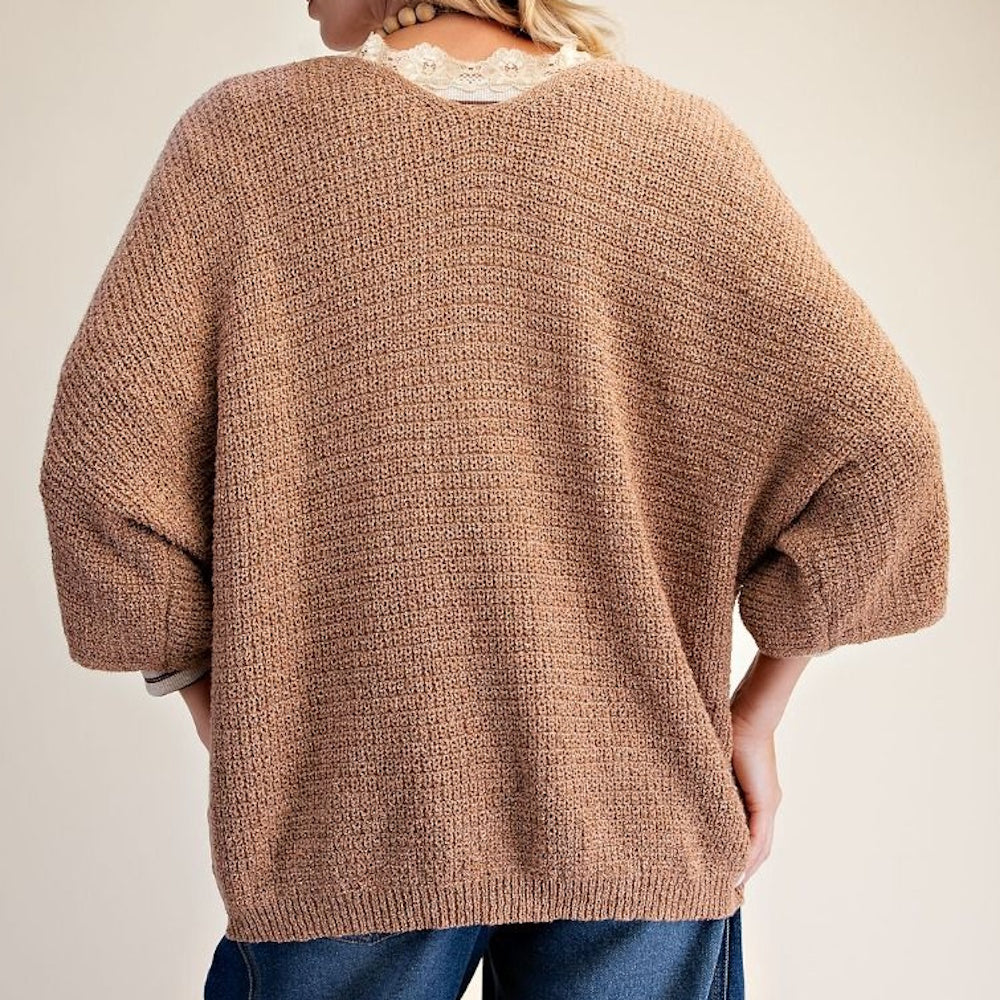 Back view of a light brown textured knit sweater featuring 3/4 sleeves and a relaxed fit.