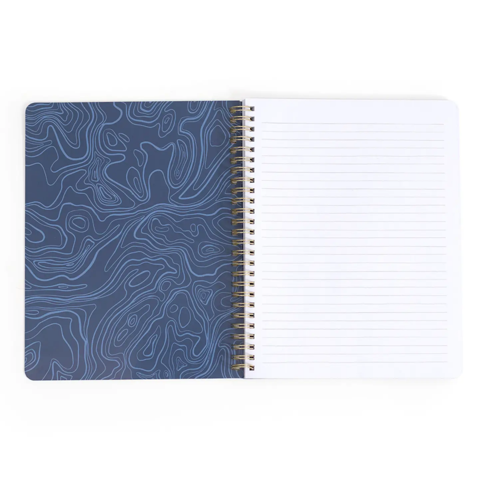 Open spiral notebook with blue topographic pattern inner cover and lined white pages.