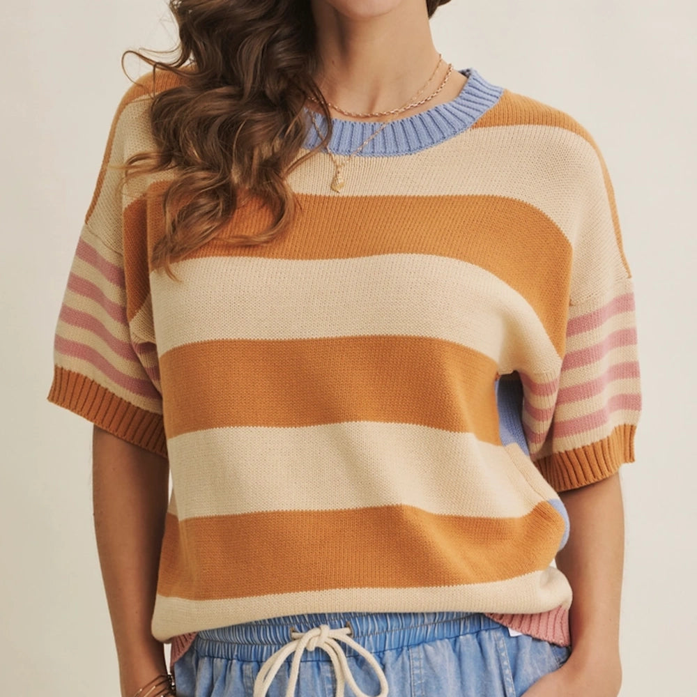 Woman in a relaxed short-sleeve knit sweater with amber, cream, and pink stripes and a blue ribbed collar.
