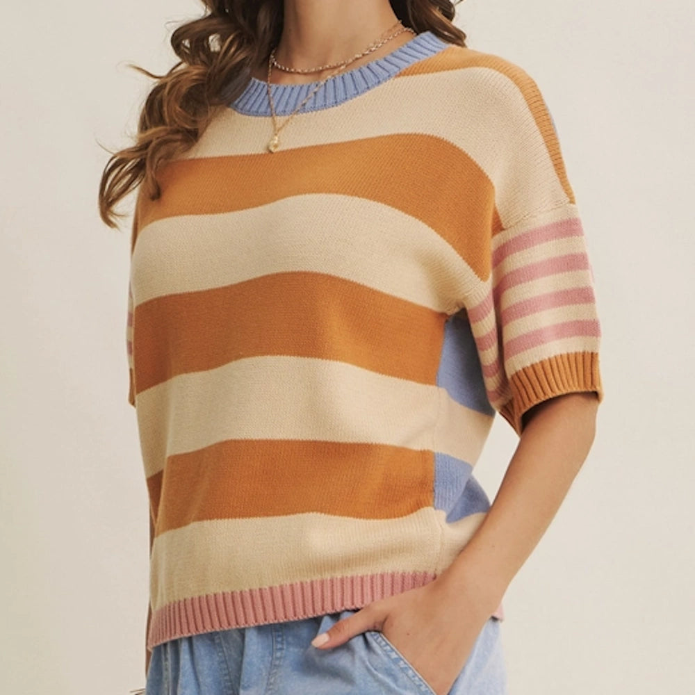 Woman wearing a multi-stripe short-sleeve knit sweater with ochre, beige, blue trim, and pink striped sleeves.