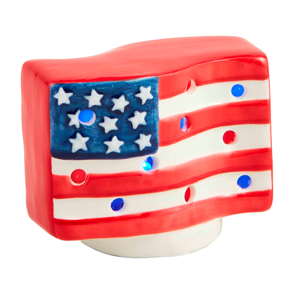 A ceramic American flag shelf sitter with red and white stripes, blue stars, and internal LED lights glowing through holes.