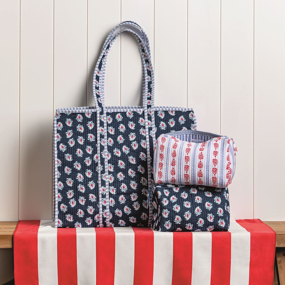 Hand-printed floral quilted tote bag and matching cosmetic pouches on a red and white striped surface.