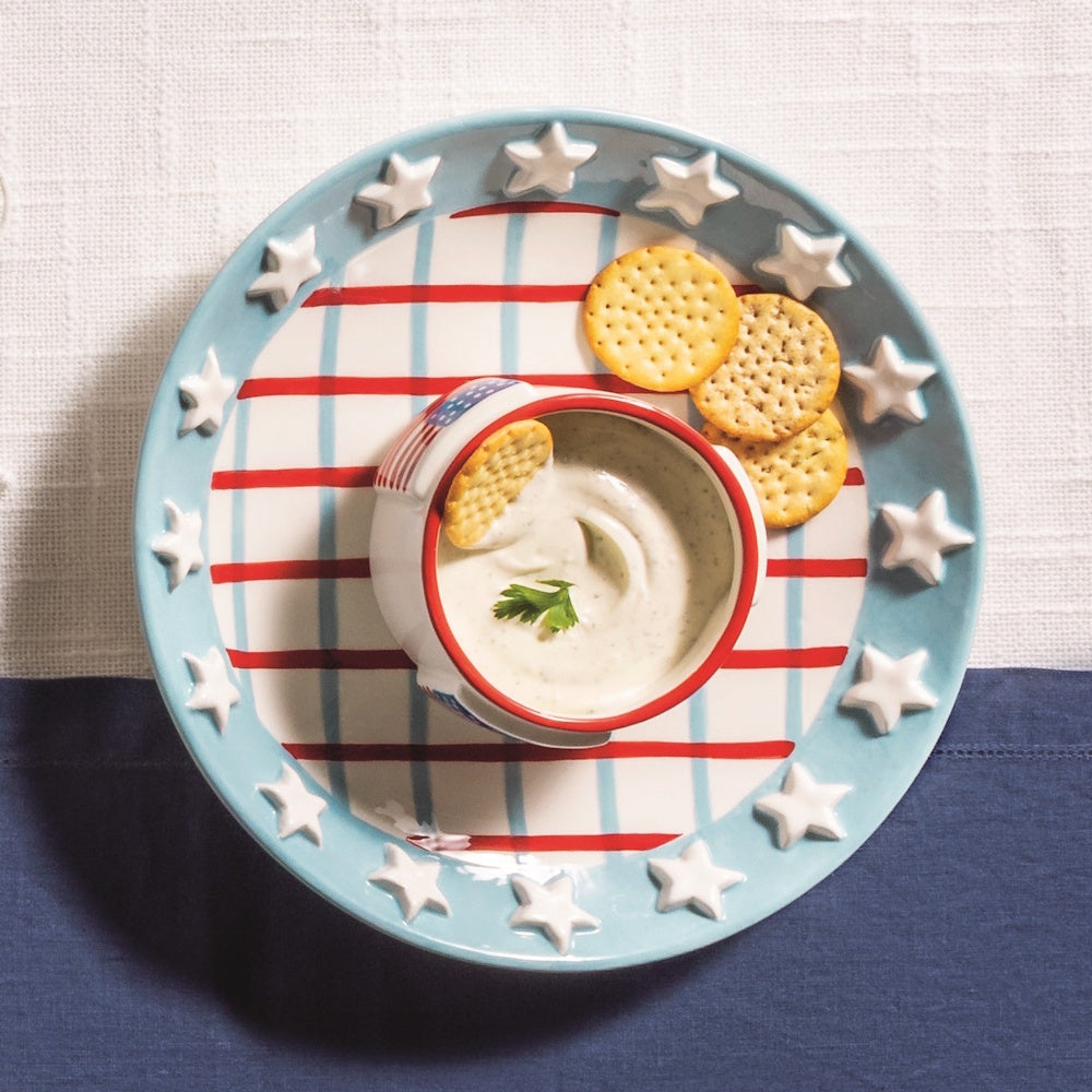 Americana chip and dip set with stars and stripes, featuring a bowl of creamy dip and round crackers on a patriotic plate.