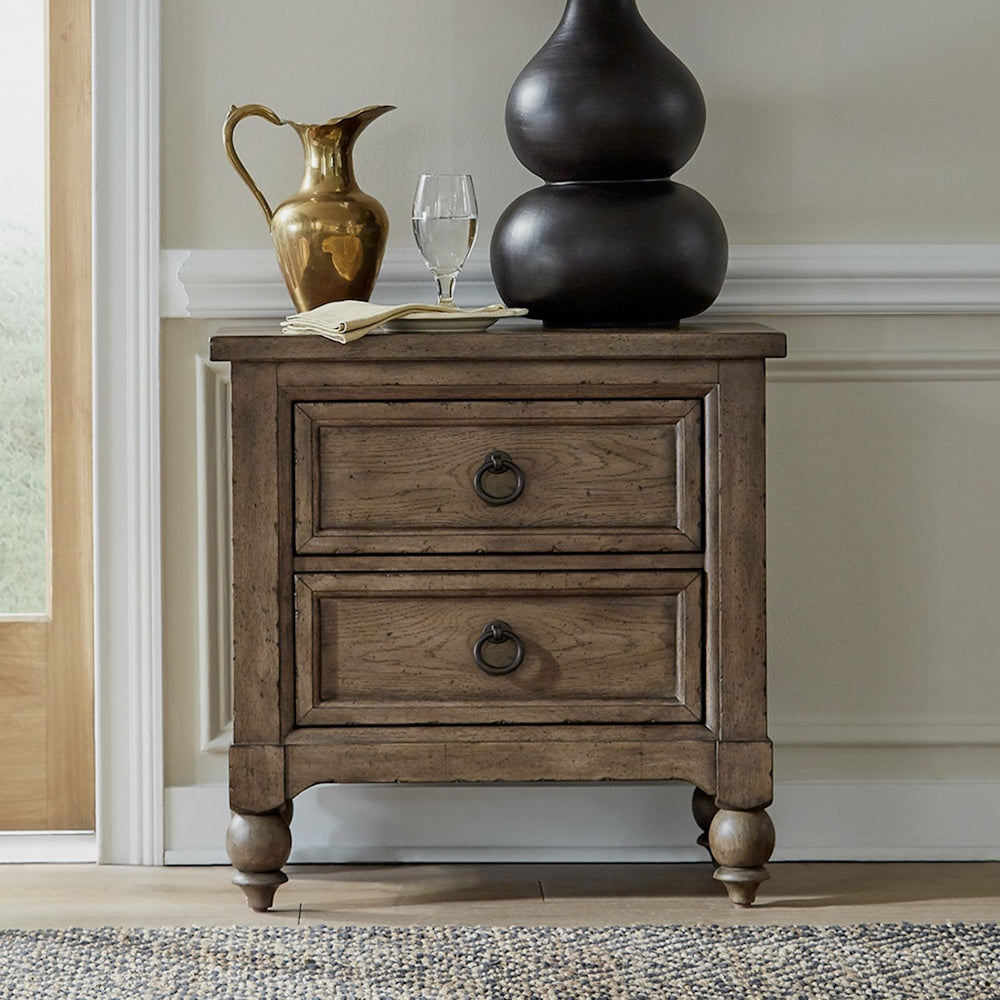 Front view of a brown wooden 2-drawer nightstand with dark ring pull handles and turned bun feet.