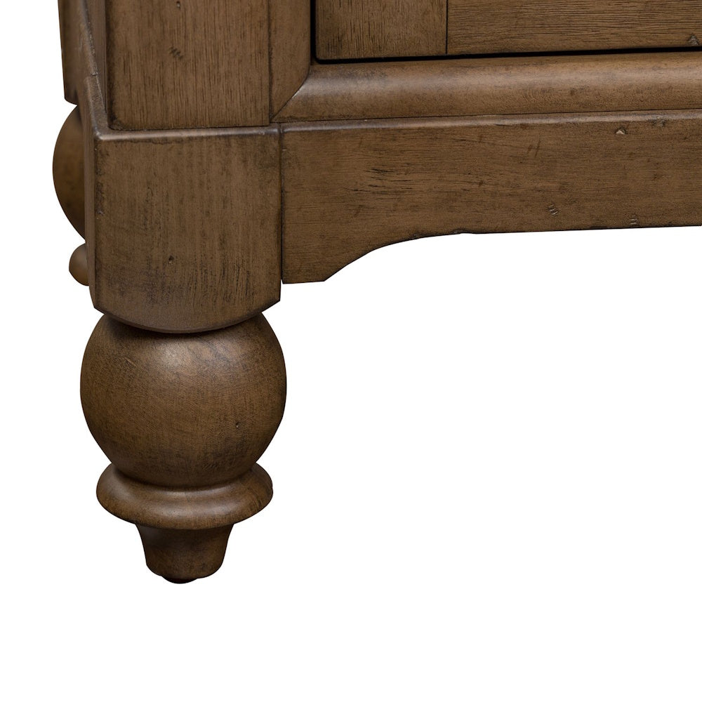 Close-up of a rustic brown wood cabinet leg featuring a turned bun foot and distressed finish.