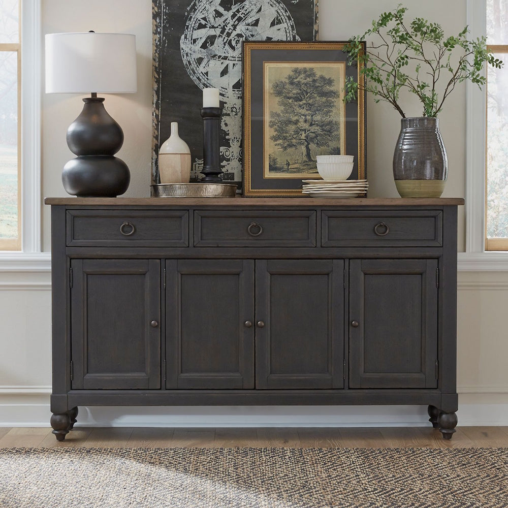 Styled black wooden hall buffet in a room, decorated with a lamp, artwork, and vase with greenery.