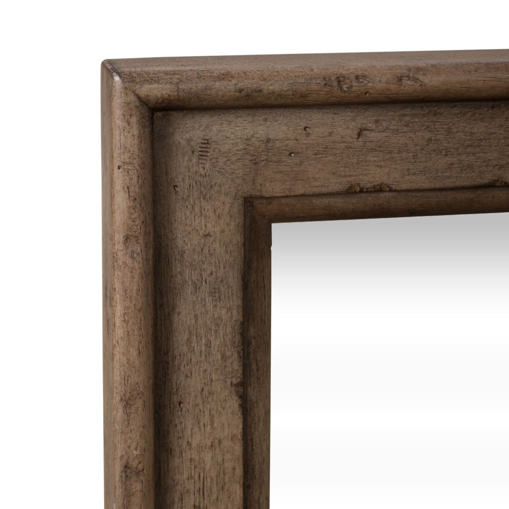 Close-up view of the corner of a rustic brown wood mirror frame with visible wood grain.