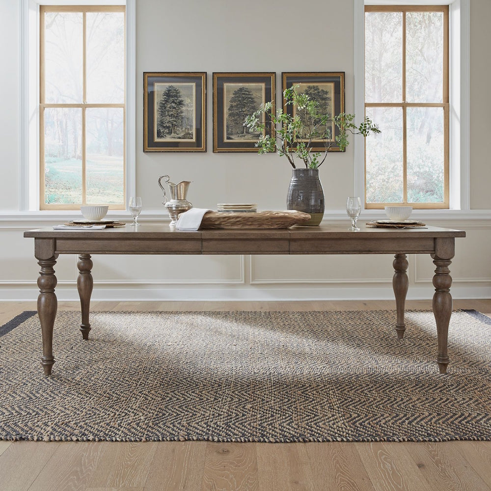 Americana farmhouse rectangular dining table set in a decorated room on a woven area rug.