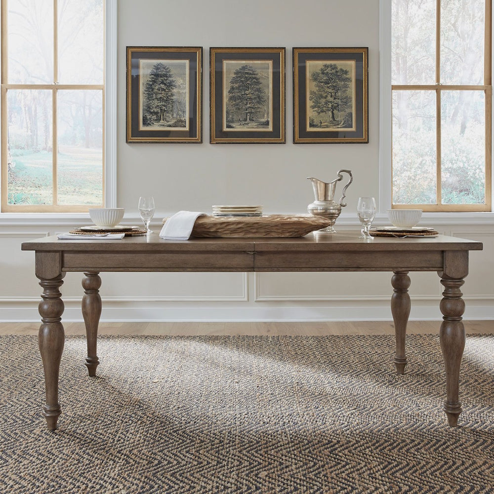 Americana farmhouse rectangular leg dining table styled with dinnerware in a bright dining room.