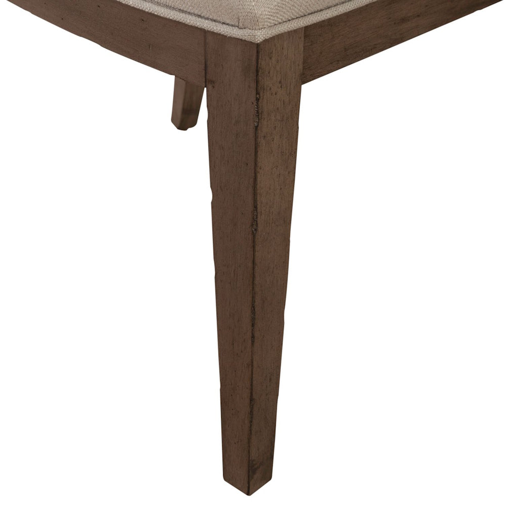 Rustic brown wooden leg base of an Americana farmhouse upholstered dining side chair.