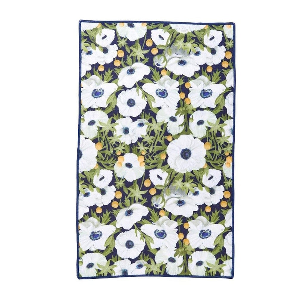 White anemone flowers with dark blue centers on a navy kitchen tea towel with green leaves and yellow accents.