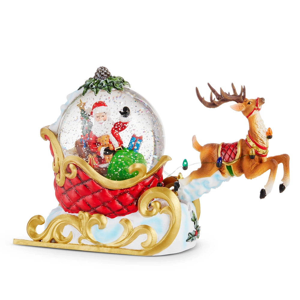 Front view of a red and gold resin Santa sleigh lighted water globe with a leaping reindeer.
