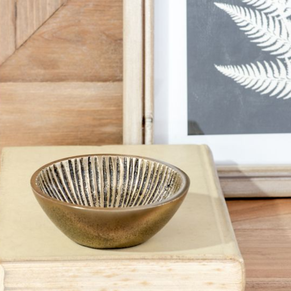 Small antique brass bowl with a ridged interior sitting on a closed book.